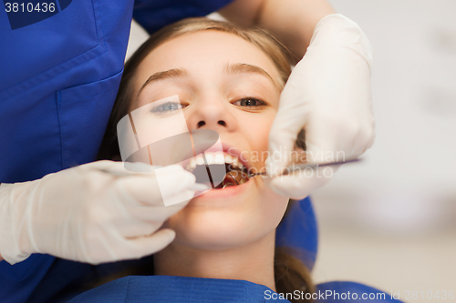 Image of female dentist checking patient girl teeth