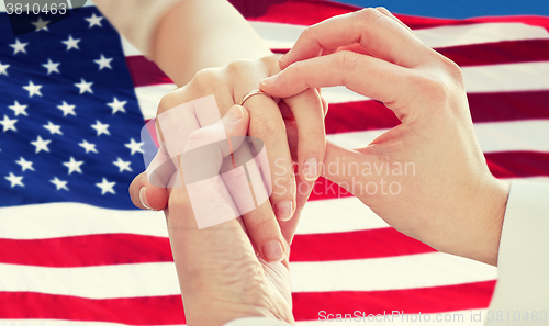 Image of close up of lesbian couple hands with wedding ring