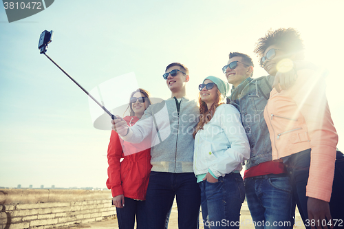 Image of smiling friends taking selfie with smartphone