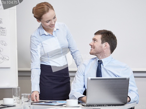 Image of smiling businesspeople with laptop in office
