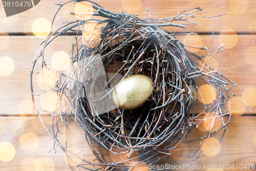 Image of close up of golden easter egg in nest on wood