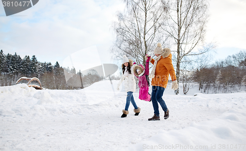 Image of happy family in winter clothes walking outdoors