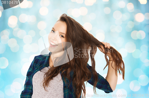Image of happy teenage girl holding strand of her hair