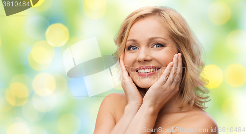 Image of smiling woman with bare shoulders touching face