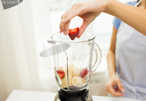 Image of close up of woman with blender making fruit shake