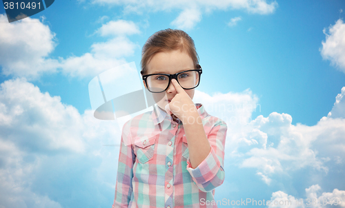 Image of happy little girl in eyeglasses over blue sky
