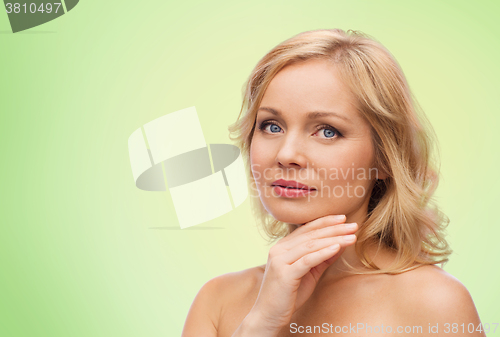 Image of smiling woman with bare shoulders touching face