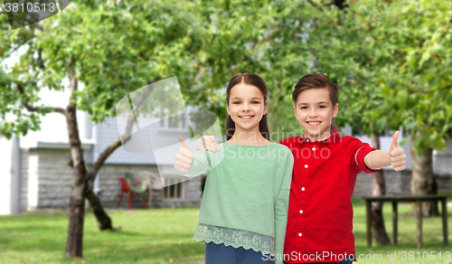 Image of happy boy and girl showing thumbs up over backyard