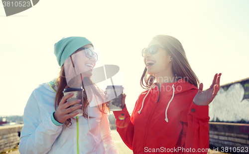 Image of happy teenage girls with coffee cups on street