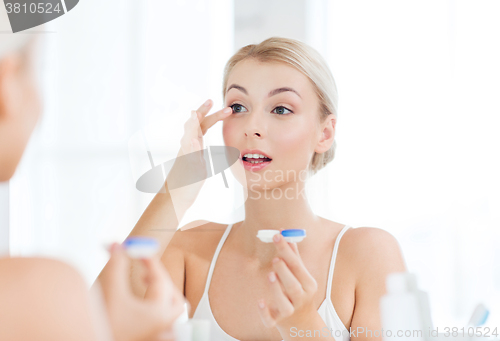 Image of young woman putting on contact lenses at bathroom