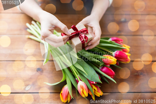 Image of close up of woman with gift box and tulip flowers