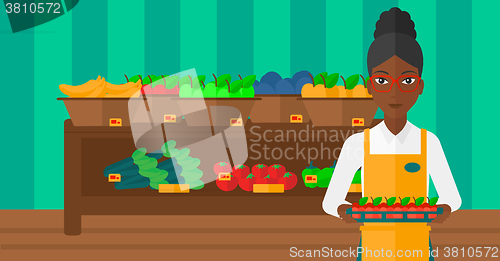 Image of Supermarket worker with box full of apples.