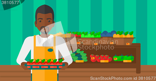 Image of Supermarket worker with box full of apples.