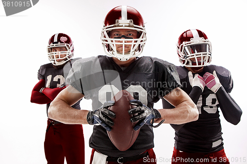 Image of The three american football players posing with ball on white background