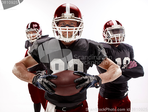 Image of The three american football players posing with ball on white background