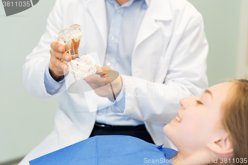 Image of close up of dentist showing teeth maquette to girl