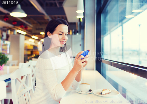 Image of smiling woman with smartphone and coffee at cafe