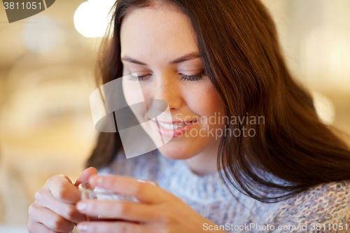 Image of smiling young woman drinking tea at cafe