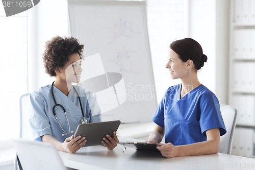 Image of happy doctors with tablet pc meeting at hospital