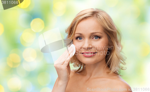 Image of happy woman cleaning face with cotton pad