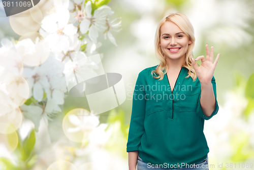 Image of smiling young woman in shirt showing ok hand sign