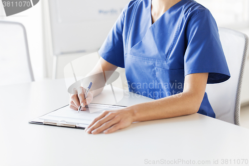 Image of close up of doctor or nurse writing to clipboard