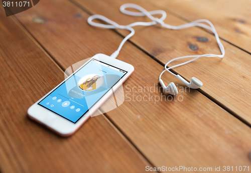 Image of close up of smartphone and earphones on wood