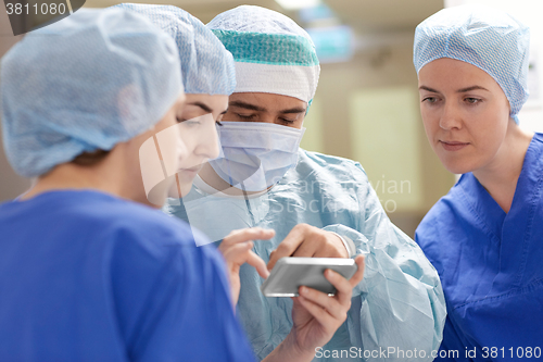 Image of group of surgeons with smartphone at hospital