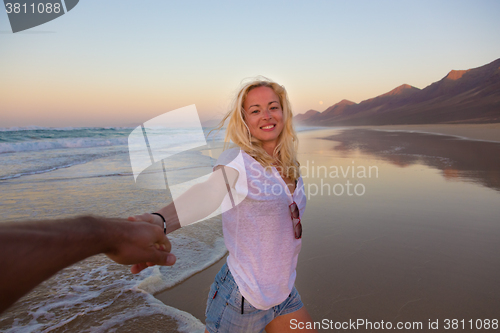 Image of Romantic couple, holding hands, having fun on beach.