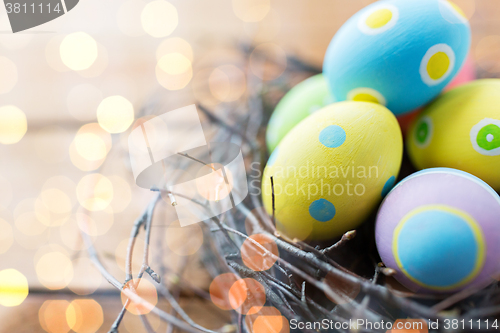 Image of close up of colored easter eggs in nest on wood