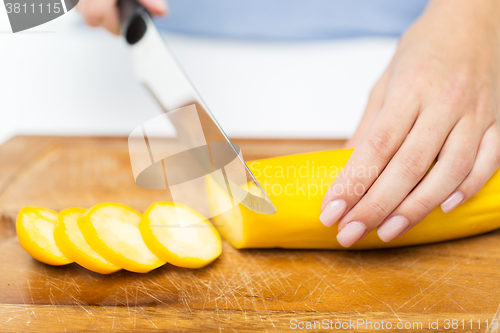 Image of close up of hands chopping squash with knife