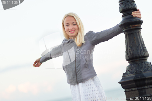 Image of Lady relaxing on fresh breeze by sea in spring.