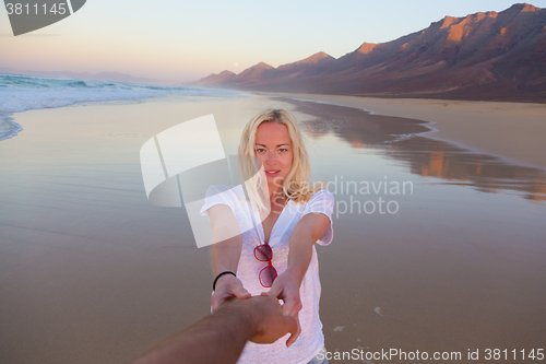 Image of Romantic couple, holding hands, having fun on beach.