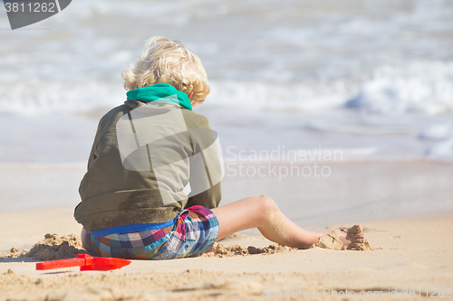 Image of Boy playing with toys on beach.