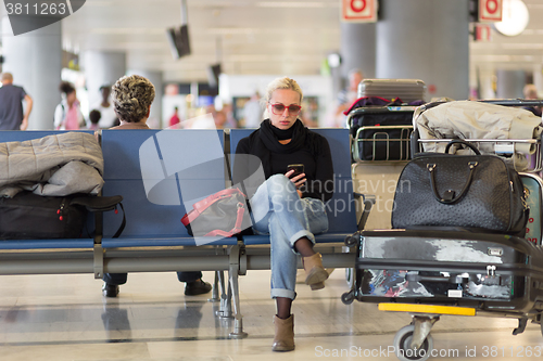 Image of Female traveler using cell phone while waiting on airport.