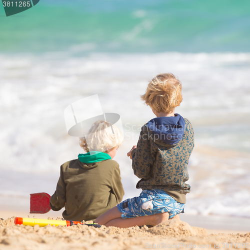 Image of Boys playing with toys on beach.