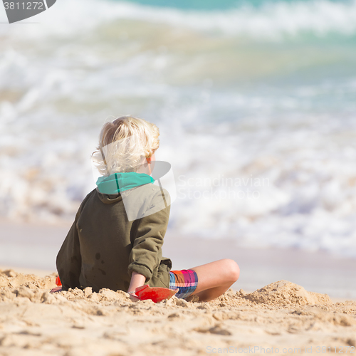 Image of Boy playing with toys on beach.