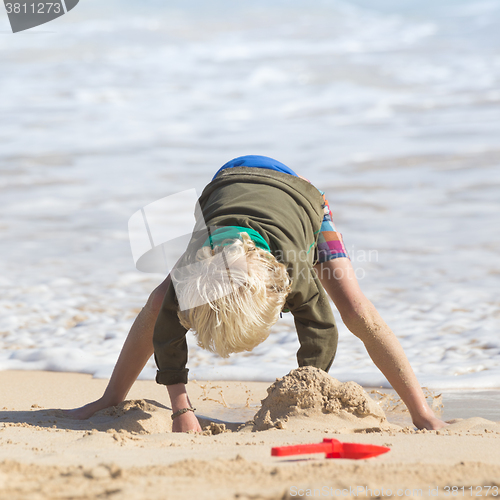 Image of Boy playing with toys on beach.