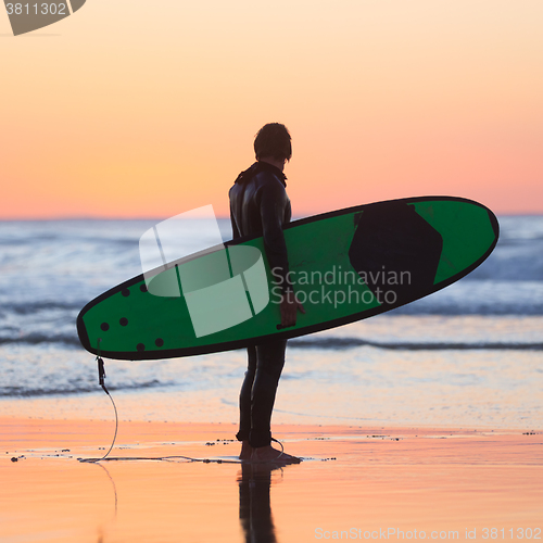 Image of Silhouette of surfer on beach with surfboard.