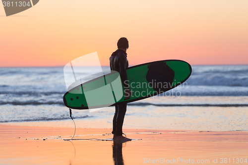 Image of Silhouette of surfer on beach with surfboard.