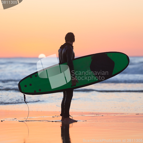 Image of Silhouette of surfer on beach with surfboard.