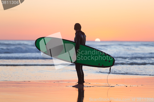 Image of Silhouette of surfer on beach with surfboard.