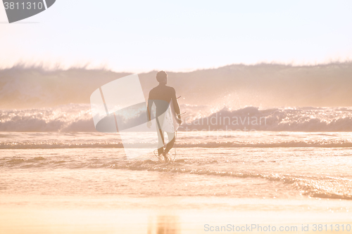 Image of Silhouette of surfer on beach with surfboard.