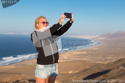 Image of Woman snaping holiday selfie on El Cofete beach