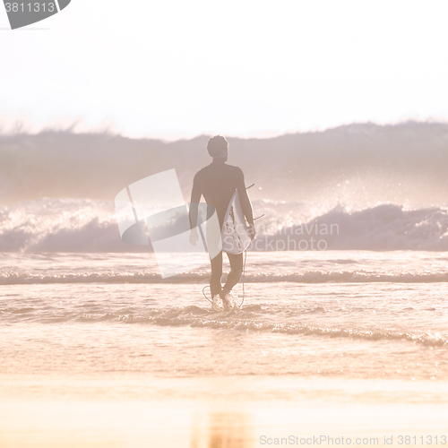 Image of Silhouette of surfer on beach with surfboard.