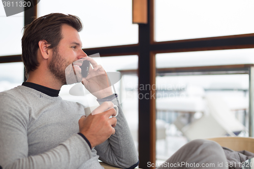 Image of Informal businessman talking on phone by window.