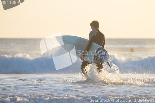 Image of Silhouette of surfer on beach with surfboard.