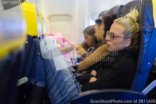 Image of Tired lady napping on airplane.