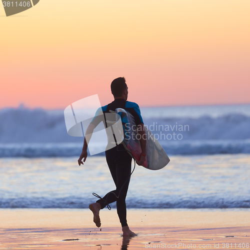 Image of Silhouette of surfer on beach with surfboard.