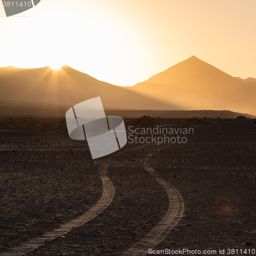 Image of Wheel tracks in sand in dramatic landscape.